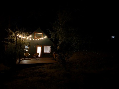 Little Pine cabin illuminated at night among pine trees